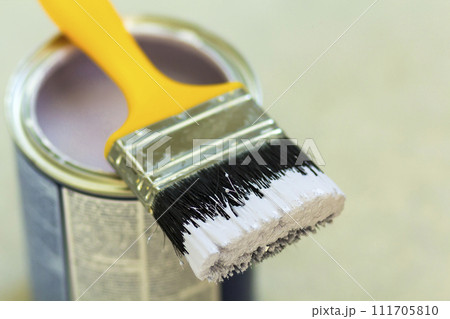 Can of white paint with paint brush over grey background. Shallow depth of field effect 111705810