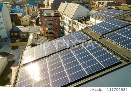 Aerial view of solar photovoltaic panels on a roof top of residential building block for producing clean electric energy. Autonomous housing concept. Aerial view of solar photovoltaic panels on a roof top of residential building block for producing clean electric energy. Autonomous housing concept. 111705923