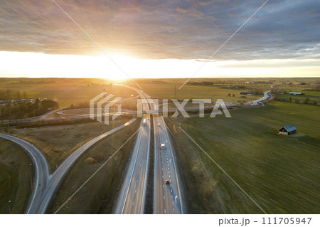 Aerial view of modern highway road intersection at dawn on raising sun background. Drone photography. Aerial view of modern highway road intersection at dawn on raising sun background. Drone photography. 111705947