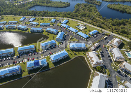 Aerial view of damaged in hurricane apartment building roofs covered with blue protective tarp against rain water leaking until replacement of asphalt shingles 111706013