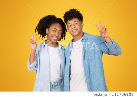 Happy young African American woman and man making peace signs with their hands 111706109