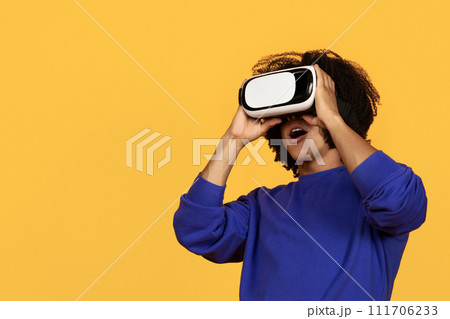 Young african american guy in casual using VR glasses Young african american guy in casual using VR glasses 111706233