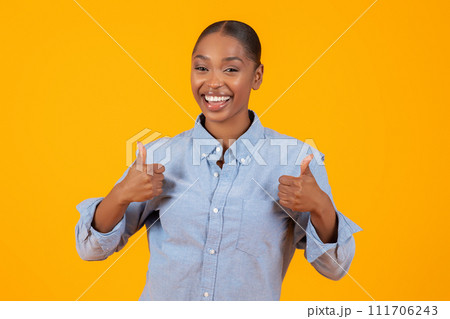 black woman showing Thumbs Up gesture with both hands, studio 111706243