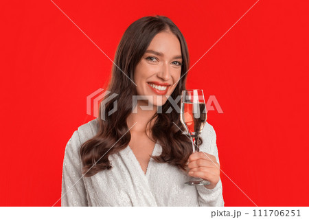 Portrait of young woman offering champagne toast on red background Portrait of young woman offering champagne toast on red background 111706251
