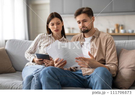 Spouses reviewing documents and using tablet at home 111706873