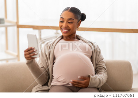 happy lady expecting baby watching funny videos and smiling 111707061