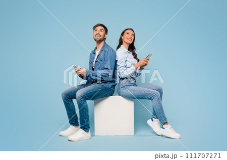 Spouses with mobiles gaze up, blue background Spouses with mobiles gaze up, blue background 111707271