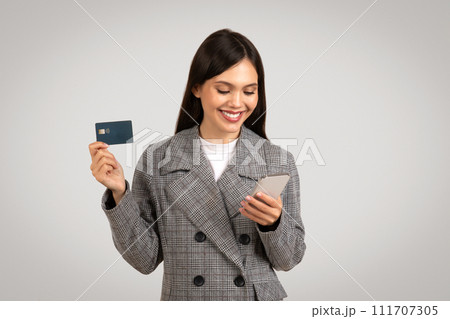 Happy businesswoman shopping online with card and phone 111707305