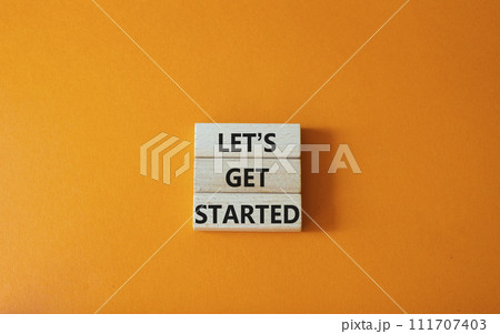 Lets get started symbol. Concept words Lets get started on wooden blocks. Beautiful orange background. Business and Lets get started concept. Copy space. 111707403
