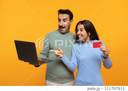Happy excited senior european man and lady point finger at laptop, show credit card 111707911