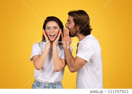 A cheerful young woman in a white t-shirt is surprised and delighted as a man A cheerful young woman in a white t-shirt is surprised and delighted as a man 111707921