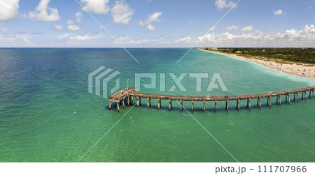 Venice fishing pier in Florida on sunny summer day. Bright seascape with surf waves crashing on sandy beach 111707966