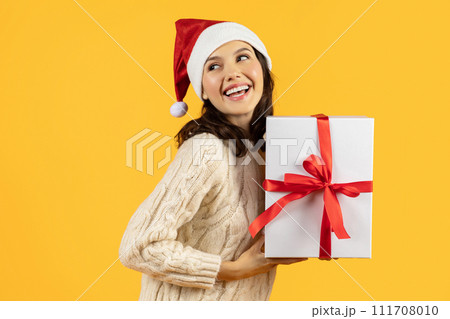 lady in festive attire poses with Xmas box, yellow backdrop 111708010