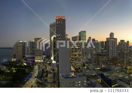 Downtown district of Miami Brickell in Florida. Skyline with illuminated high skyscraper buildings and street with cars and Metrorail traffic in modern american megapolis 111708333