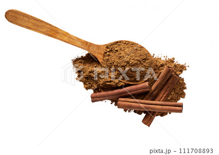 cinnamon powder in a wooden scoop and cinnamon sticks isolated on a white background ,top view. cinnamon powder in a wooden scoop and cinnamon sticks isolated on a white background ,top view. 111708893