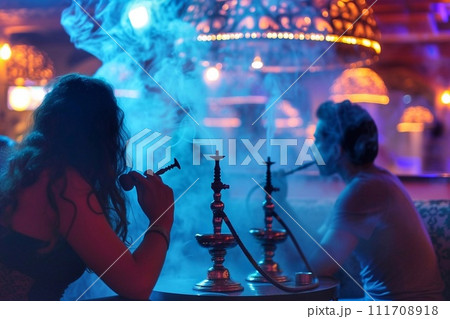 Smoking hookah in a bar at night. 111708918