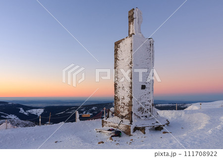 Stone column with height quota 1603 m in snezka, mountain on the border between Czech Republic and Poland, winter, sunrise time. Stone column with height quota 1603 m in snezka, mountain on the border between Czech Republic and Poland, winter, sunrise time. 111708922