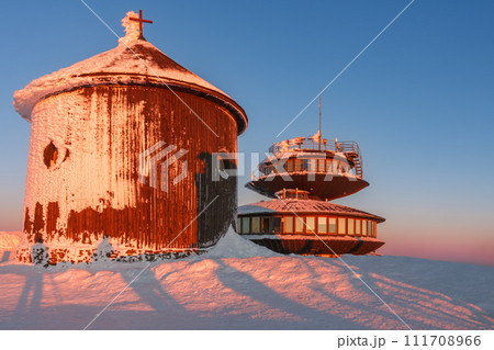 Winter, sunrise time, wooden Roman catholic chapel and disc shaped meteorological observatory in snezka, mountain on the border between Czech Republic and Poland. Winter, sunrise time, wooden Roman catholic chapel and disc shaped meteorological observatory in snezka, mountain on the border between Czech Republic and Poland. 111708966