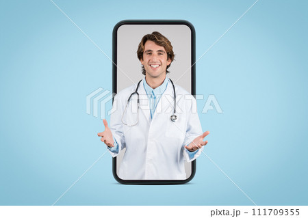Friendly male doctor in white medical coat having online appointment with patient, posing in huge smartphone screen 111709355