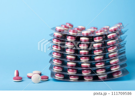 Close up of a colorful pills bicolor pills wrapped in the blister. Three tablets out of the blister. 111709586