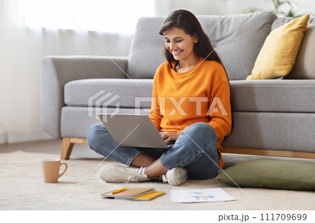 Happy millennial indian lady typing on laptop, home interior Happy millennial indian lady typing on laptop, home interior 111709699