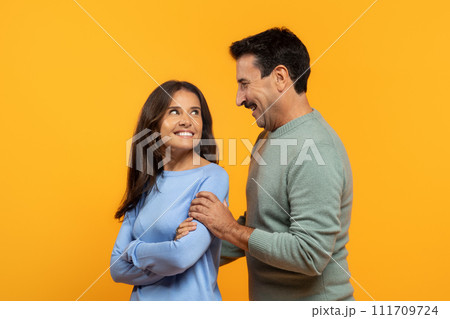 Two cheerful senior man and woman, share light-hearted moment, laughing and looking at each other 111709724