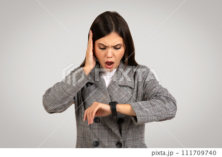 Stressed businesswoman checking time on smartwatch 111709740