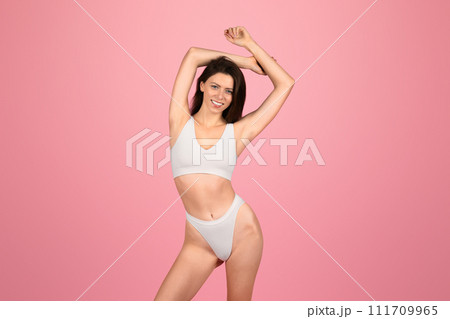 An exuberant young woman with chestnut hair joyfully stretches her arms above her head An exuberant young woman with chestnut hair joyfully stretches her arms above her head 111709965