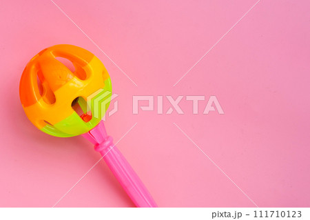 Colorful baby rattle on pink background. Copy space 111710123