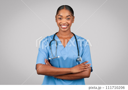 Smiling confident black millennial doctor surgeon, nurse in blue uniform with crossed arms on chest Smiling confident black millennial doctor surgeon, nurse in blue uniform with crossed arms on chest 111710206