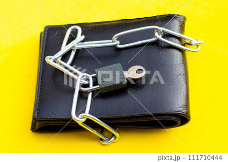 Black wallet in chains closed padlock on yellow background. Black wallet in chains closed padlock on yellow background. 111710444