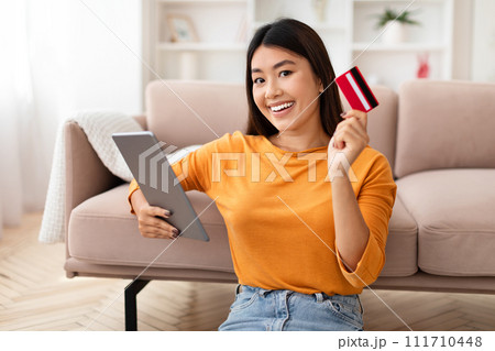 Positive young asian woman using credit card and digital tablet Positive young asian woman using credit card and digital tablet 111710448