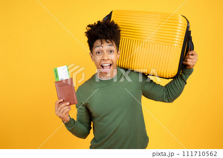 Excited young black guy tourist with suitcase and passport Excited young black guy tourist with suitcase and passport 111710562