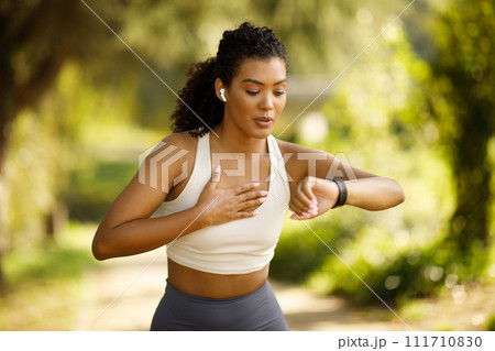 woman runner checking smartwatch pausing and breathing in run outdoors 111710830