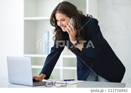 Mature Businesswoman Talking On Phone Working On Laptop In Office 111710842