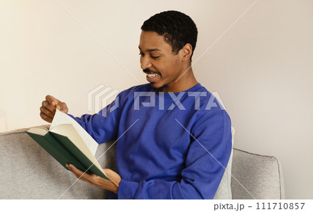 African American young man engrossed in literature, reading book indoor 111710857