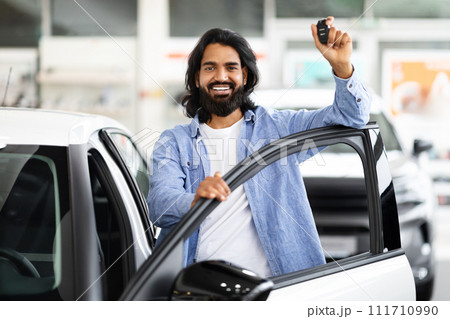 Wealthy eastern businessman buying new car in luxury auto showroom Wealthy eastern businessman buying new car in luxury auto showroom 111710990
