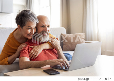 Happy Senior Couple Using Laptop Computer, Browsing Internet At Home 111711017