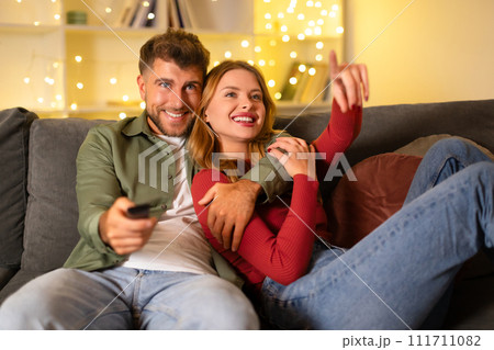Couple cuddling and watching TV at home Couple cuddling and watching TV at home 111711082