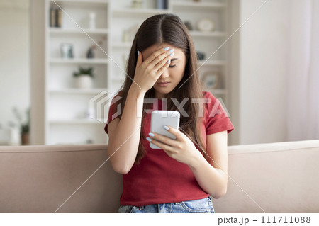 Bad News. Upset Asian Woman Touching Head After Reading Message On Smartphone 111711088