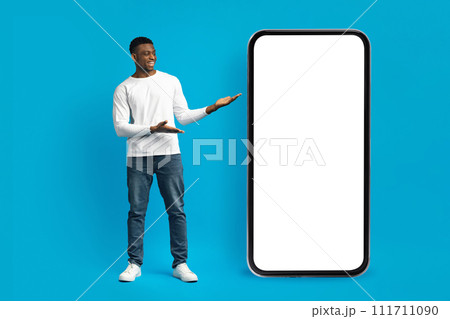 Stylish millennial african american guy posing by huge smartphone 111711090
