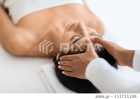 Serene eastern woman receiving head massage at spa Serene eastern woman receiving head massage at spa 111711189