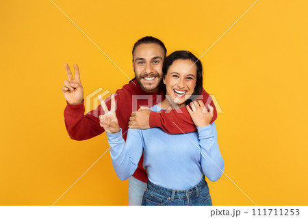 Loving cheerful millennial couple posing on yellow background 111711253