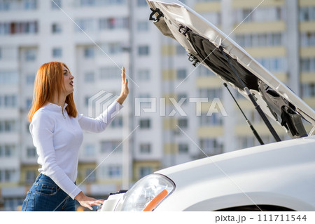 Young stressed woman driver standing near broked car with open hood. Young stressed woman driver standing near broked car with open hood. 111711544