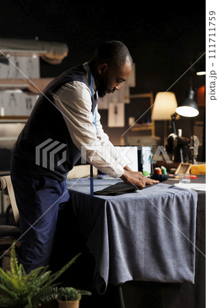 Expert suitmaker meticulously working on suit blazer in atelier shop workspace with precision and expertise. Professional fashion designer finishing sartorial business attire for client comission 111711759
