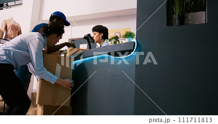 African american courier showing shipment report to worker, discussing online orders details in clothing store. Manager standing at counter desk, preparing packages for shipping in modern boutique African american courier showing shipment report to worker, discussing online orders details in clothing store. Manager standing at counter desk, preparing packages for shipping in modern boutique 111711813