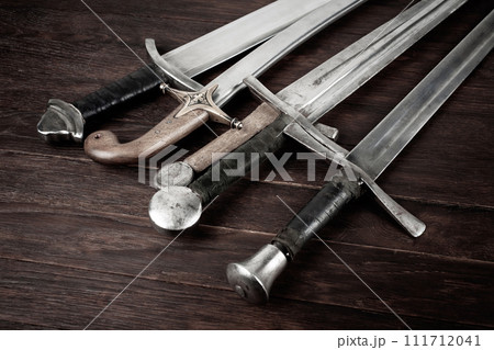 Swords and sabre on wooden background. 111712041