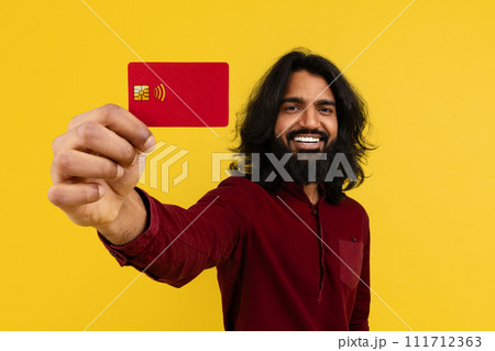 Cheerful young indian guy showing bank card Cheerful young indian guy showing bank card 111712363