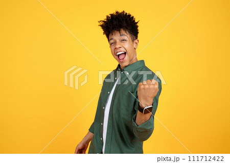 Excited young african american guy clenching fist 111712422