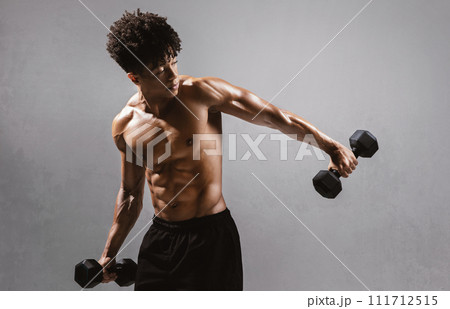 shirtless sportsman holding weights flexing strong arms on gray backdrop shirtless sportsman holding weights flexing strong arms on gray backdrop 111712515
